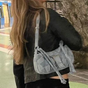 Quiltad jeans axelväska med spänne - Säljer en ljusblå quiltad axelväska i jeansmaterial med justerbar rem och snyggt bältesspänne i silver. Väskan har patchwork-look med synliga sömmar🦋