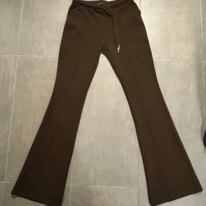 Bruna bootcut mjukisbyxor från Zara - Mörkbruna mjukisbyxor från Zara i bootcut-modell med snörning i midjan. Sköna och stilrena med utsvängda ben och mjukt material, perfekta för en chill och trendig look.