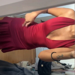 Vinröd omlottklänning med knyt - Säljer en vinröd kortklänning med omlott och knyt i nacken. Helt ny inköpt men faller mig inte riktigt i smaken. Passar XXS och XS.