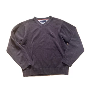 Tommy Hilfiger tröja - Snygg brun v-ringad tröja från Tommy Hilfiger i 100% bomull. Klassisk design med diskret logga på bröstet och ribbade muddar vid ärmslut och nederkant. Perfekt för dig som gillar stilrena och tidlösa plagg.