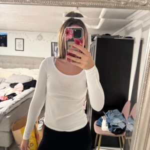 Vit långärmad topp med rund hals - En basic vit långärmad topp med rundad halsringning. Sitter tight och är perfekt att styla med jeans eller kjol. Enkel och stilren design som funkar till många olika looks.