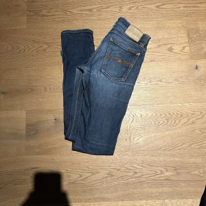 Blåa Nudie Jeans  - Tja säljer mina blåa nudie jeans. Dom är i bra skick litet hål vid knät men syns inte allt för mycket vid användning, Storleken är 27/34 och passformen är slimfit. Kom vid minsta fundering 
