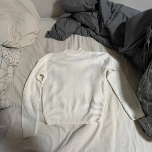 Vit ribbstickad tröja från FB Sister - Säljer en vit ribbstickad tröja från FB Sister i storlek XXS. Tröjan har lång ärm, rund hals och är gjord i ett mjukt stickat material. Perfekt för lager-på-lager och enkel att matcha med jeans eller kjol.