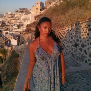 Blå paisleymönstrad långklänning - Säljer en flowy långklänning i blått med paisleyinspirerat mönster och djup v-ringning. Klänningen har halterneck och är ärmlös, perfekt för varma dagar. Tyget är lätt och luftigt, vilket gör den superbekväm och snygg till sommaren.