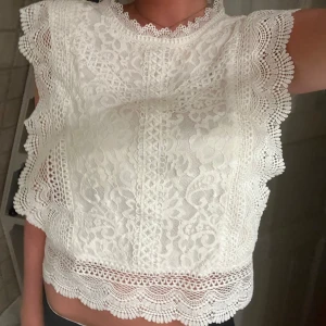 Vit spetsblus - Superfin vit blus i spets med blommigt mönster. Blusen är ärmlös och har en hög, rund halsringning med dekorativ spets. Knappt använd💕💕