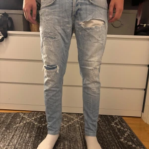 Dondup Ljusblå slitna jeans med skinny fit - Säljer ett par ljusblå jeans med skinny passform och flera slitningar och hål på benen för en riktigt skön stil, det är väldigt mycket slitningar men inget som inte går o fixa med patches. Priset är inte hugget i sten.