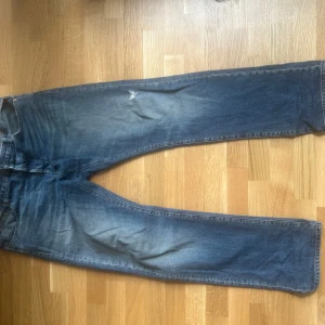Blå Replay jeans straight fit - Säljer ett par klassiska blå jeans från Replay i straight fit. Jeansen har en snygg tvätt med slitningar och ljusare partier på låren. De har fem fickor och normal passform, perfekta till en avslappnad stil.