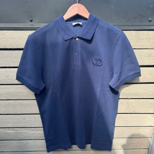 Blå Dior Piké - Otroligt vacker piké från Dior. Pikén är endast provad då den inte passar mig, därav är skicket precis som nytt. Storlek S, men passar M eftersom den har oversized passform. Box och shoppingbag medföljer även. ✅Använd ”Köp nu” knappen så är denna snygga piké påväg till dig inom 6 timmar. ✅