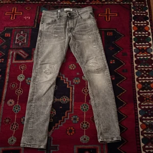 Replay grå jeans med slitningar - Säljer ett par grå jeans från Replay med coolt tvättad look och slitna detaljer på benen. Klassisk femficksmodell med Replay-logga på fickan och bakfickor med unik söm. Raka ben och normal passform, perfekta till sneakers. Är bara använda 3-5 gånger! Pris kan diskuteras skriv om ni har några frågor👍