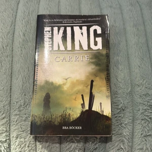 Carrie - En modern klassiker av Stephen King! Carrie är en bok om utanförskap, mobbning och oväntade krafter. Perfekt för dig som gillar spänning och starka berättelser. Omslaget har en mystisk och mörk känsla som lockar till läsning.