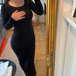 Svart långärmad långklänning - Säljer en svart långklänning med lång ärm och rund halsringning. Klänningen har en tight passform som framhäver figuren och är tillverkad i ett mjukt och stretchigt material. Perfekt för dig som gillar minimalistisk och stilren look.