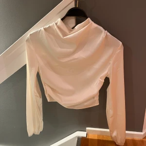 Vit croppad blus med draperad krage - Säljer en stilren vit blus med lång ärm och croppad passform. 