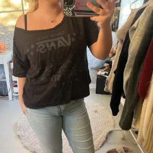 Svart Vans t-shirt med tryck - Svart t-shirt från Vans med coolt tryck och stjärnor framtill. Modellen är loose fit med korta ärmar och bred halsringning som kan bäras offshoulder. Mjuk bomull som känns skön mot huden, perfekt för dig som gillar streetstyle.