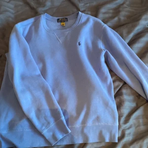 Ljusblå sweatshirt från Polo Ralph Lauren - Säljer en ljusblå sweatshirt från Polo Ralph Lauren i utmärkt skick. Perfekt nu inför hösten och vintern på grund av den fodrade insidan. Storlek 160cm. Ny pris ligger på cirka 1000kr, mitt pris 349kr