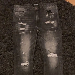 Svarta ripped jeans Supply & Demand - Säljer ett par svarta jeans från Supply & Demand med slitna detaljer och ripped look. Jeansen har skinny passform, klassiska fem fickor och coola slitningar framtill. Perfekta för dig som gillar streetstyle och vill sticka ut lite extra.