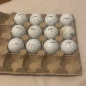 Titleist TruFeel Golfbollar 12 styck - En samling Titleist TruFeel golfbollar, perfekta för dig som vill ta ditt golfspel till nästa nivå. Bollarna är i bra skick och levereras i praktisk förpackning. Passar både nybörjare och erfarna golfare som vill ha känsla och kontroll på banan.