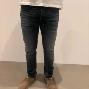 Mörkblå slim jeans - Snygga mörkblå jeans med slim Glenn och lätt slitning på låren. Klassisk femficksmodell med normal midja och smal passform hela vägen ner. Perfekta för dig som gillar en tajt look och vill ha ett par stilrena jeans till vardags.