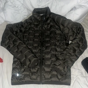 Svart dunjacka från McKinley, Small - Säljer en svart dunjacka från McKinley i storlek Small. Jackan har quiltad design, hög krage och dragkedja framtill. Perfekt för kyliga dagar och enkel att matcha med det mesta. Snygg och funktionell med praktiska fickor med dragkedja.