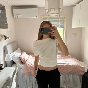 Asymmetrisk topp Zara - Asymmetrisk topp från zara. Man kan ha den på lite olika sätt, antingen rakt eller med ena axeln off shoulder. Sitter åt vid midjan och är lite lösare upptill. Den är i stretchigt material. Storlek M på lappen men passar S lika bra.  Skriv om du har frågor🩷