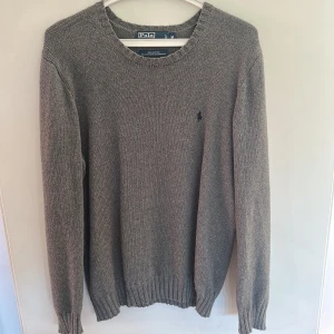 Grå stickad tröja från Polo Ralph Lauren - Snygg grå stickad tröja från Polo Ralph Lauren i 100% bomull. Klassisk rund hals. Storlek M.