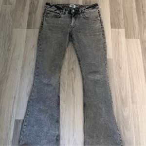 Grå bootcut jeans från 157 - Snygga grå jeans från 157 med bootcut-modell och klassisk femficksdesign. Jeansen har hög midja och är tillverkade i ett mjukt denimtyg som ger en skön passform. Perfekta för dig som gillar en retroinspirerad look med utsvängda ben.