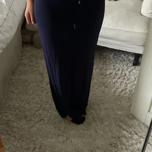 Mörkblå långkjol - Enkel och stilren mörkblå långkjol i mjukt tyg. Kjolen har en rak och tight passform som sitter snyggt över höfterna och faller rakt ner mot anklarna. 