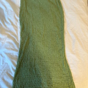 Grön långkjol med crinkle-effekt - Säljer en snygg grön långkjol med crinkle-effekt. Kjolen har en rak passform och resår i midjan för extra komfort. Perfekt för dig som gillar en chill och stilren look. Materialet känns lätt och luftigt, perfekt för varmare dagar.