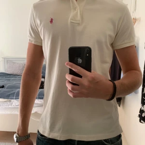 Ralph Lauren Piké  - Ralph Lauren pike i färgen cream white med rosa logga. Pikén är HELT oanvänd och har därmed inga defekter alls✅. Storleken är M slim fit. Hör av er vid frågor!😁
