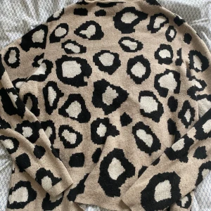 Beige leopardmönstrad tröja - Säljer en supercool beige tröja med leopardmönster i svart och grått. Den är perfekt för att sticka ut lite extra i höst och vinter. Tröjan är långärmad och gjord i ett mjukt material som känns skönt mot huden. Passar perfekt till både jeans och kjol!