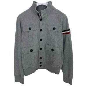Moncler Cardigan - Tvärfet grå moncler cardigan i jättebra skick. Strlk M. Retail:800€. Liten defekt vid innerlappen där tvättningsmärket är(inget som påverkar användningen, bild skickas på pm. Vid fler frågor skriv ett meddelande. Allt gott, mvh.