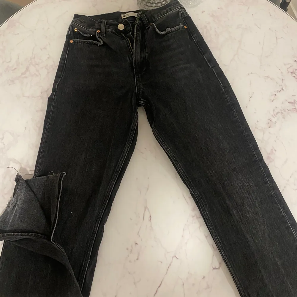 Säljer ett par svarta jeans från Gina tricot i storlek 34. De har en klassisk design med en rak passform och en snygg, sliten look vid fållen. de har även slits längst ner på benen. Perfekta för en avslappnad stil!. Jeans & Byxor.