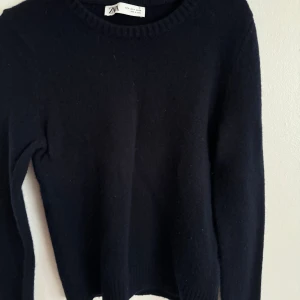 Svart tröja från Zara - Säljer en stickad marinblå tröja från Zara i storlek M. Tröjan är perfekt för både vardag och fest och har en klassisk design med långa ärmar. Den är tillverkad i ett mjukt material som känns skönt mot huden. Passar perfekt till höst- och vintergarderoben! 