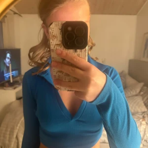 Blå ribbad croppad tröja - Snygg blå ribbad tröja med croppad passform och v-ringning. Perfekt för en trendig look.
