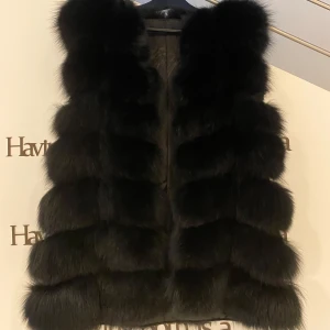 Svart pälsväst - Elegant svart pälsväst med en lyxig och fluffig design. Perfekt för att hålla sig varm och stilfull under kallare dagar. Västen har en klassisk passform och är ett statement-plagg för garderoben.