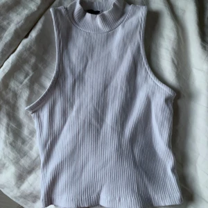 Vit ribbad ärmlös topp från lager 157 - Säljer en stilren vit ribbad topp från 157. Den är ärmlös med en hög krage, perfekt för lager-på-lager eller som den är. Passar både till vardags och mer uppklädda tillfällen. Aldrig använd! Hör av er vid frågor, pris kan diskuteras! ❤️