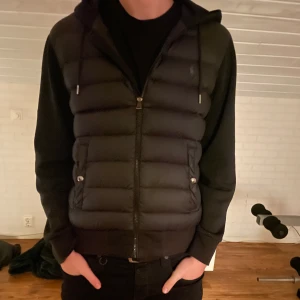 Svart Ralph Lauren cardigan/hybrid jacka - Säljer denna snygga Ralph Lauren cardigan/hybrid jacka som inte längre säljs. Jackan är storlek M men passar storlek S med. Skicket är 8,5/10. Finns en liten synlig defekt vilket är det lilla märket på höger arm men det är relativt litet, inget man tydligt ser, utöver det är jackan i bra skick! Hör gärna av dig vid frågor, funderingar eller önskar mer bilder!