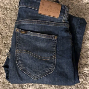 Lee jeans - Snygga blå jeans från Lee med klassisk femficksdesign och knappgylf. Perfekta för en avslappnad stil. Märkeslogga på bakfickan och insidan av linningen. Slim passform. Säljs för 129 Nypris 1000.