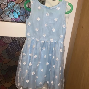 Blå blommig finklänning  - Med knappar i polyester. Nästan aldrig använd så som ny! Storlek: 128