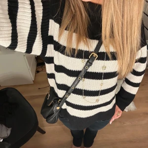 Svartvit randig stickad tröja - Säljer en mysig svartvit randig stickad tröja med långa ärmar. Perfekt för kyligare dagar och enkel att matcha med olika outfits. Tröjan har en klassisk design med breda ränder.