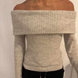 Beige ribbad offshoulder tröja - Snygg beige offshoulder tröja med ribbad struktur. Perfekt för en stilren look, med långa ärmar och en mjuk känsla. Passar utmärkt till både jeans och kjol.