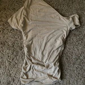 Beige oneshoulder topp från Gina Tricot - Säljer en stilren beige oneshoulder topp från Gina Tricot. Perfekt för en trendig look med sin unika skärning vid sidorna. Passar bra till både jeans och kjol.