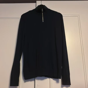 Tröja från Jack & Jones - Säljer en stilren blå tröja från Jack & Jones med dragkedja vid halsen. Tröjan har långa ärmar och är perfekt för en avslappnad look. Passar bra till både jeans och chinos.