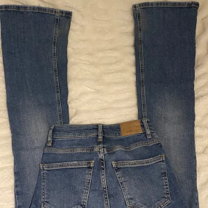 Blå jeans med bootcut - Säljer ett par blåa bootcutjeans i storlek 32 som är midwaist från Gina Tricot. Defekter som finns visas på sista sidan💙