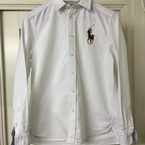 Ralph Lauren skjorta - Snygg vit skjorta från Ralph Lauren i mycket bra skick då skjortan endast använts ett fåtal gånger. Jag säljer denna skjorta eftersom att jag har växt ur den. Priset är diskuterbart, skriv i dm för frågor!