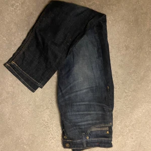 Mörkblå jeans - Snygga mörkblå jeans med klassisk femficksdesign och kontrastsömmar. Perfekta för en avslappnad stil eller den så kallade grisch stilen, de har en slim passform och benslutet tajtar ihop sig. De har en knappgylf och är tillverkade i ett slitstarkt material. Pris går att diskutera! 