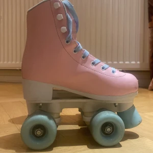 Bubbelgum Rosa rullskridskor från Rookie och skydd - Säljer ett par bubblegum rosa rullskridskor från märket Rookie (nypris var drygt cirka 1200) . De har ljusblå hjul och snörning. Perfekta för unga åkare som vill glida runt med stil. Inkluderar även ett säkerhetspaket från Impala i matchande rosa färg som originalet kostar 369 kr. I säkerhetspaket innehåller två knäskydd. Två armbågskydd och två stycken handledsskydd.  Rullskridskorna har använts ett fåtal gånger. Säljer för att de har blivit för små för mig (storlek 32). 