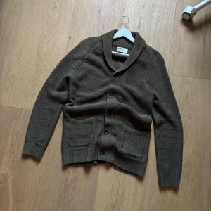 Brun kofta från Dobber - Snygg brun kofta från Dobber med knappar framtill och två praktiska fickor. Perfekt för kyligare dagar med sin stickade design och långa ärmar. En klassisk och stilren look som passar till många tillfällen. Om du undrar hur den sitter på så kolla min annons med den blåa dobber cardiganen, den sitter samma som den✌️