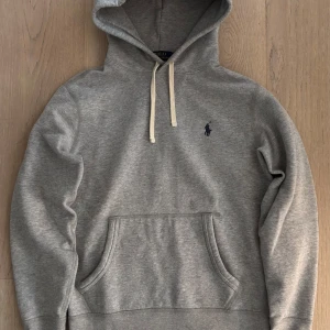 Grå Ralph Lauren Hoodie - Fet Ralph Lauren hoodie i extremt bra skick, endast använd ett fåtal gånger.  Inköpt från deras hemsida i höstas, nypris runt 2000 kr. Prutmån finns, hör även av er om mått eller annat!