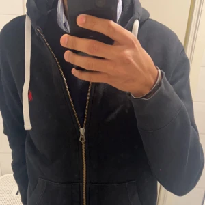 Ralph lauren zip hoodie - Säljer min populära Ralph lauren zip hoodie som är svart med rött märke. Storlek är L men skulle säga att den är liten i storleken, brukar vanligtvis ha S/M. Skick typ 7 /10, lite faded med tecken på användning därav det billiga priset
