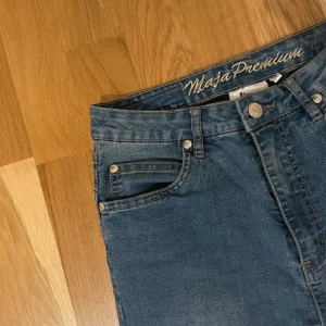 Blå jeansbyxor från Maja Premium - Snygga blå jeansbyxor från Maja Premium med klassisk femficksdesign. De har en knapp och dragkedja framtill och är högmidjade för en bekväm passform. Perfekta för en stilren look.